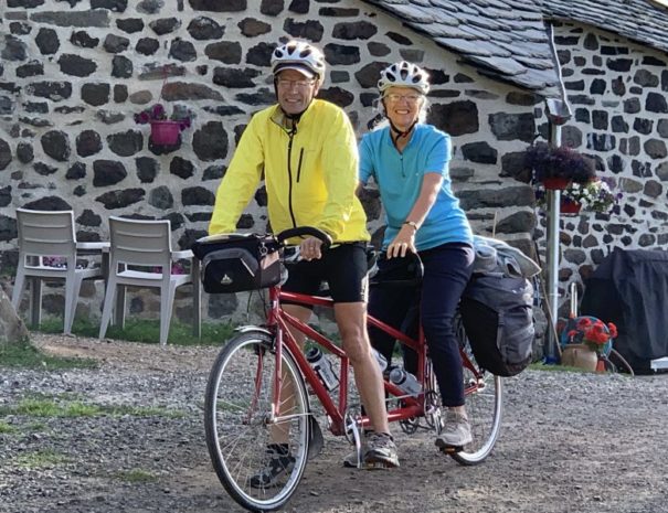 Couple de randonneur sur leur vélo tandem devant la ferme